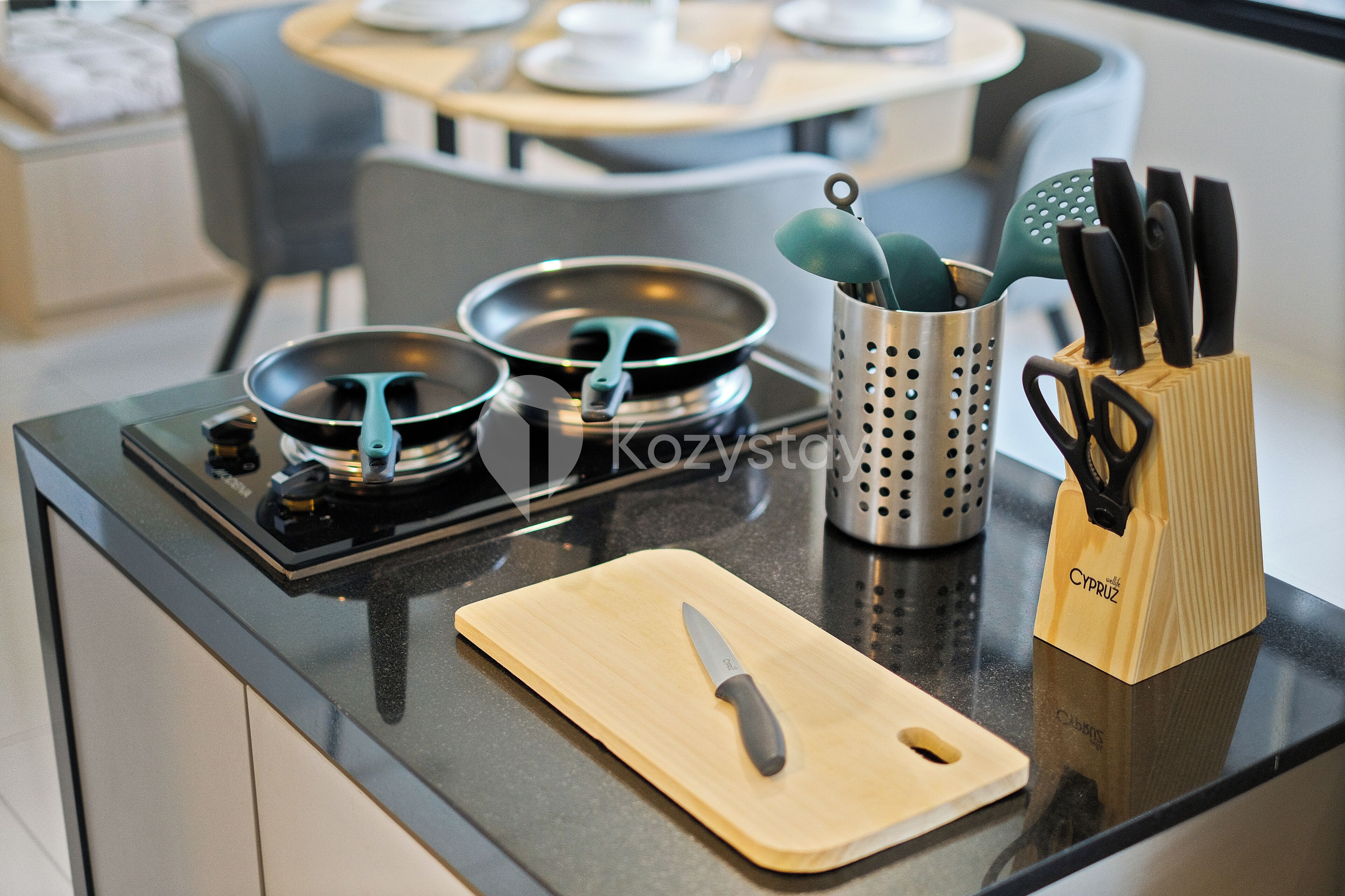A kitchen counter with a cutting board, a knife, a pot, and a utensil holder.