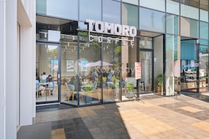 En moderne café, der hedder "TOMORO COFFEE", med store glasfacader og et indrettet siddeområde indeni.