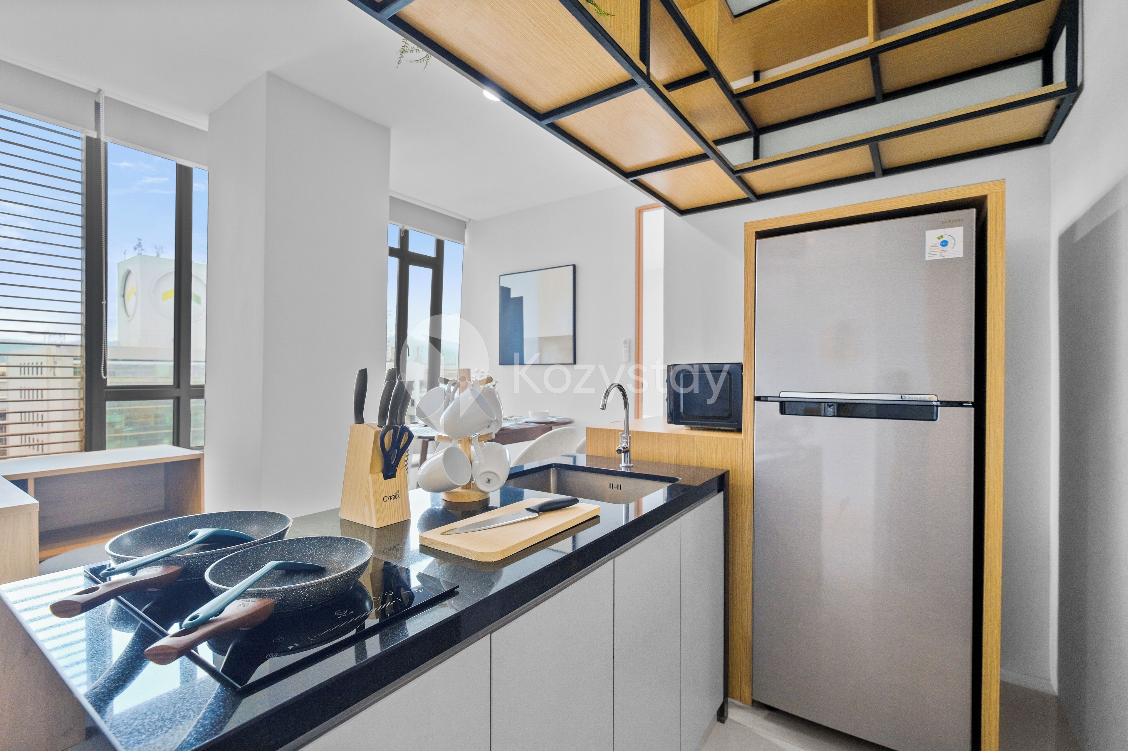 A modern kitchen with a black countertop, stainless steel appliances, and wooden accents.