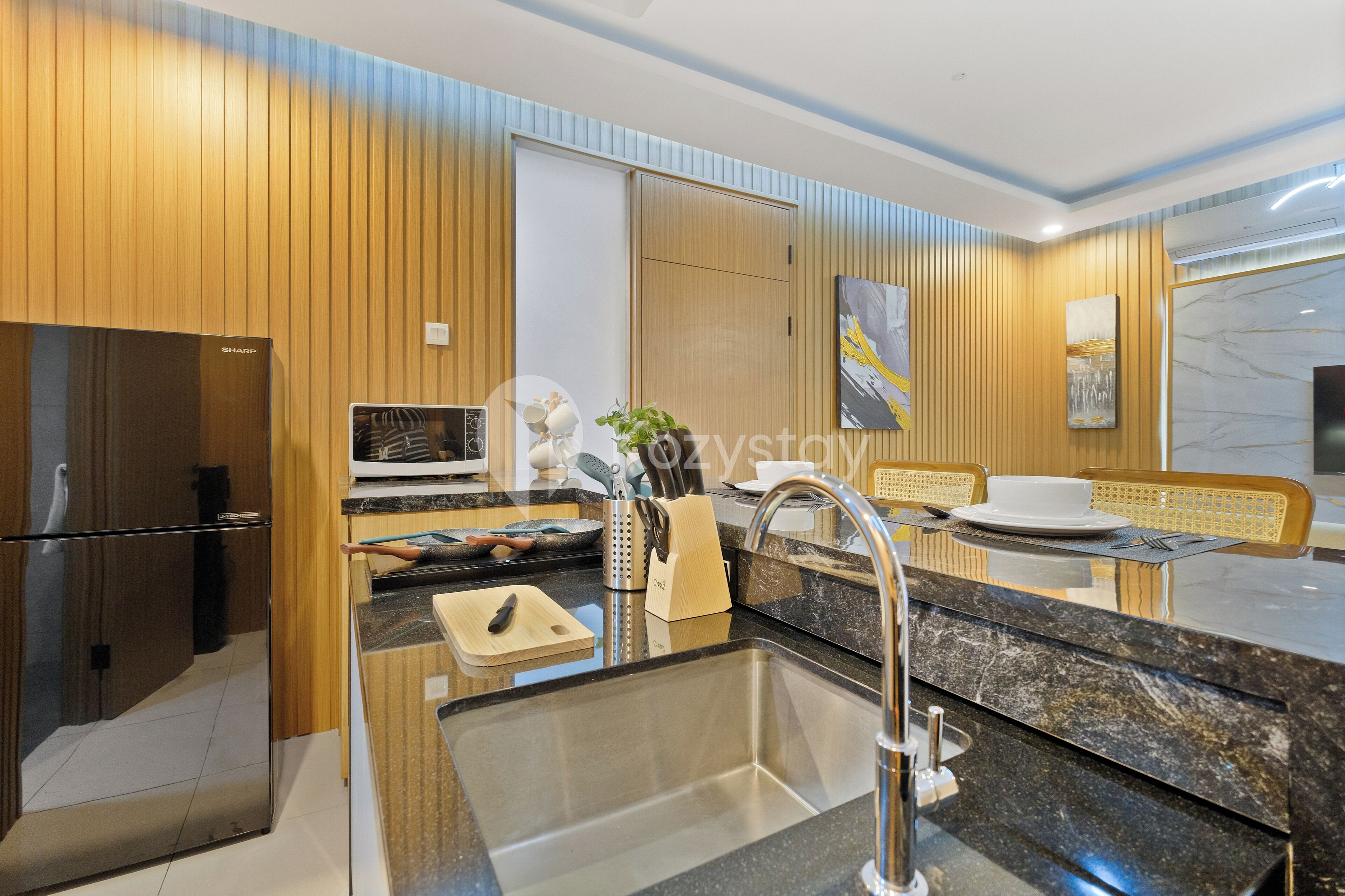 Una cucina moderna con rivestimenti in legno, un lavello in acciaio inossidabile e un forno a microonde.