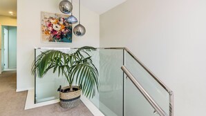 A modern interior with a glass railing, a potted plant, and a decorative light fixture. - Auckland Golden Phoenix Holiday Homes (Auckland)