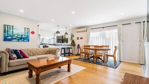 A spacious living room with a sofa, coffee table, and dining area. - Auckland Golden Phoenix Holiday Homes (Auckland)