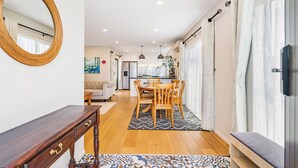 A modern kitchen with a dining area, wooden furniture, and a patterned rug. - Auckland Golden Phoenix Holiday Homes (Auckland)