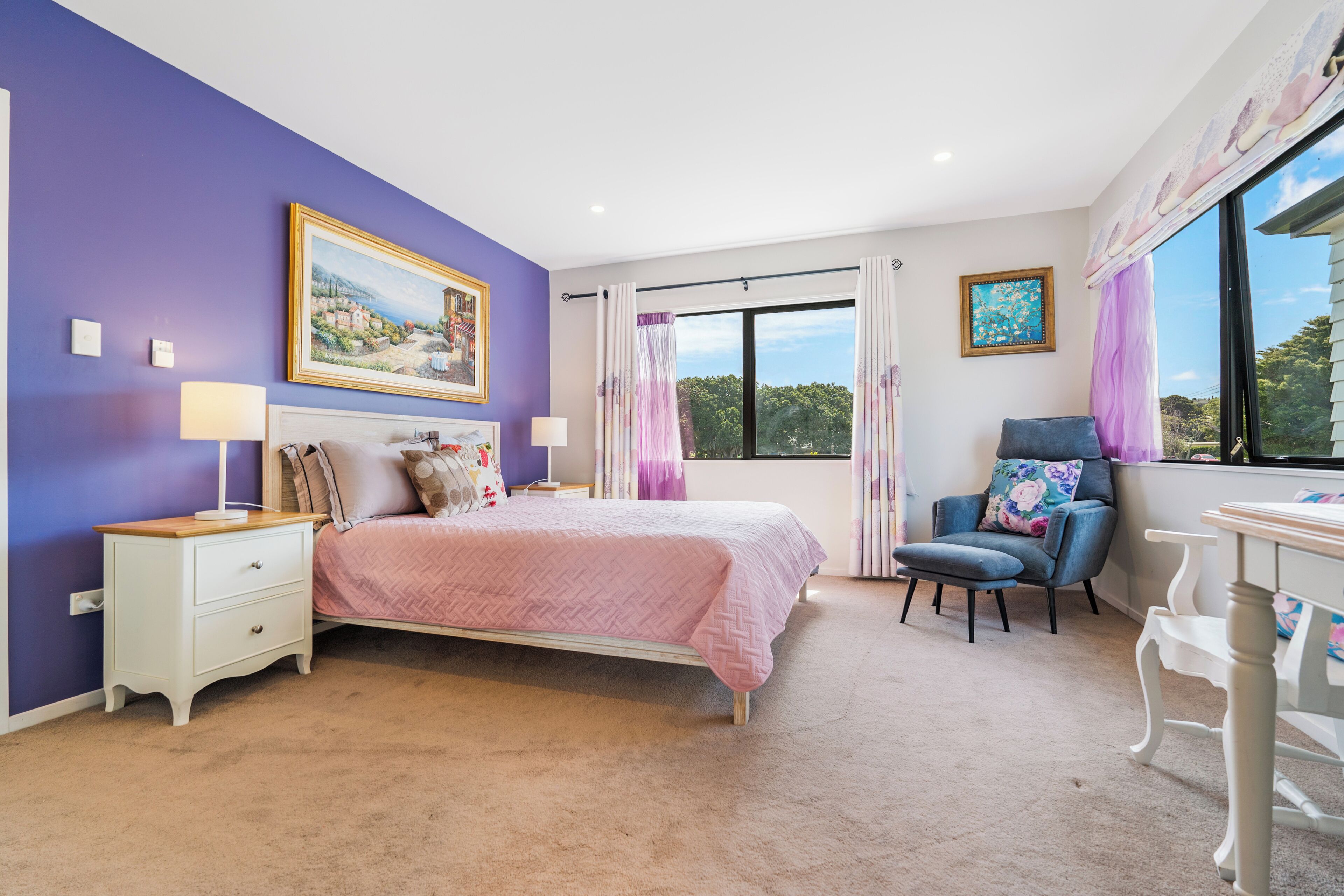 Quarto com cama, mesas de cabeceira, uma cadeira e janela com cortinas.