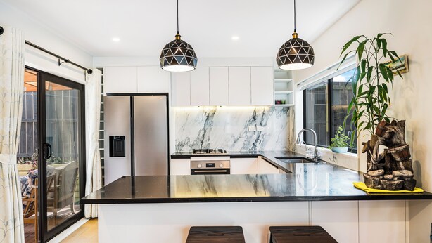 A modern kitchen with a marble countertop, two pendant lights, and a large window. - Auckland Golden Phoenix Holiday Homes (Auckland)