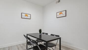 A conference room with a dark wooden table, four black chairs, and two framed artworks on the walls.