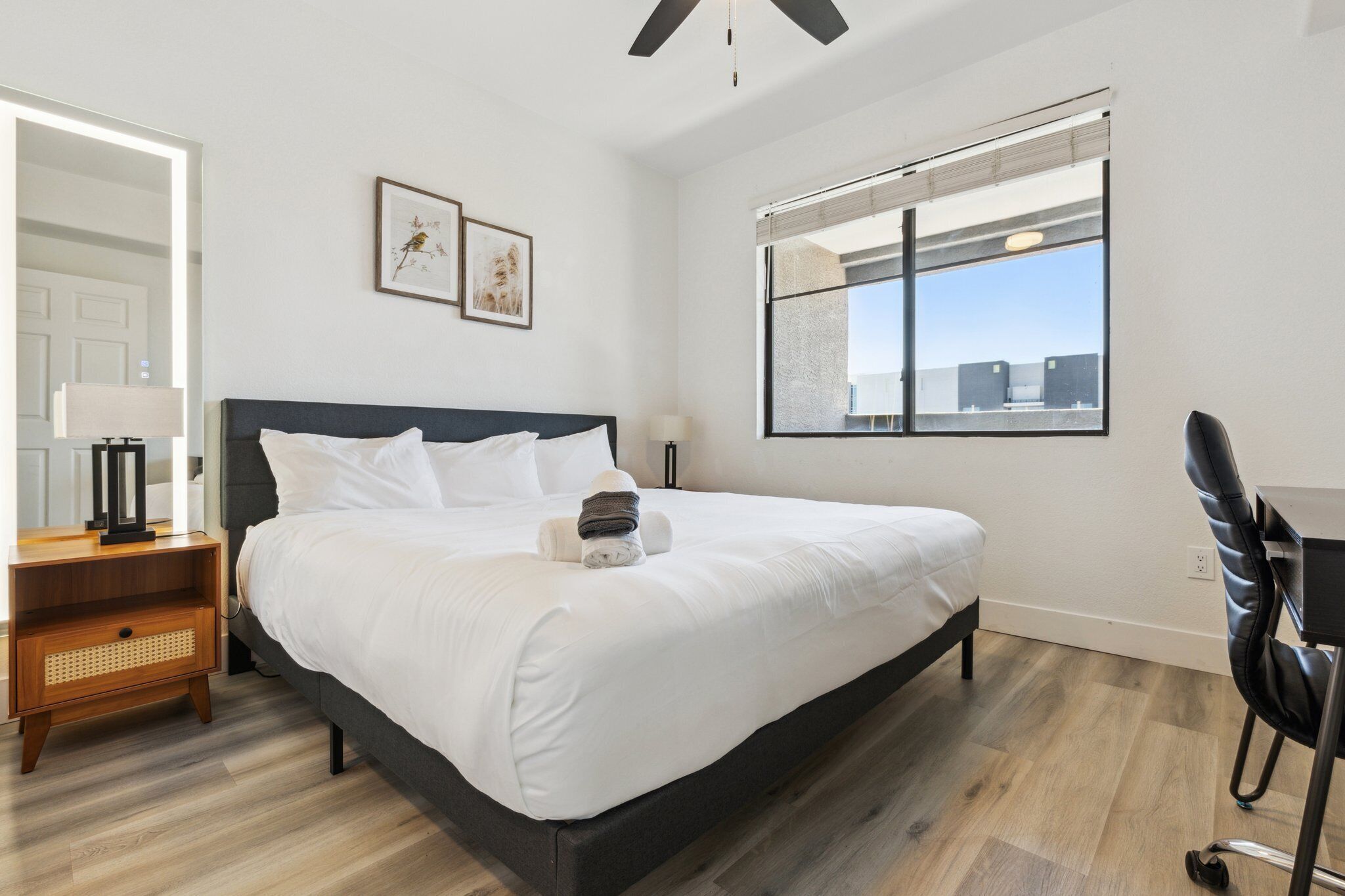 A modern hotel room with a large bed, a desk, and a window with a city view.