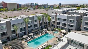 A modern hotel with a rooftop pool, multiple floors, and a view of the surrounding cityscape. - CozySuites at Zone Westgate (Glendale)
