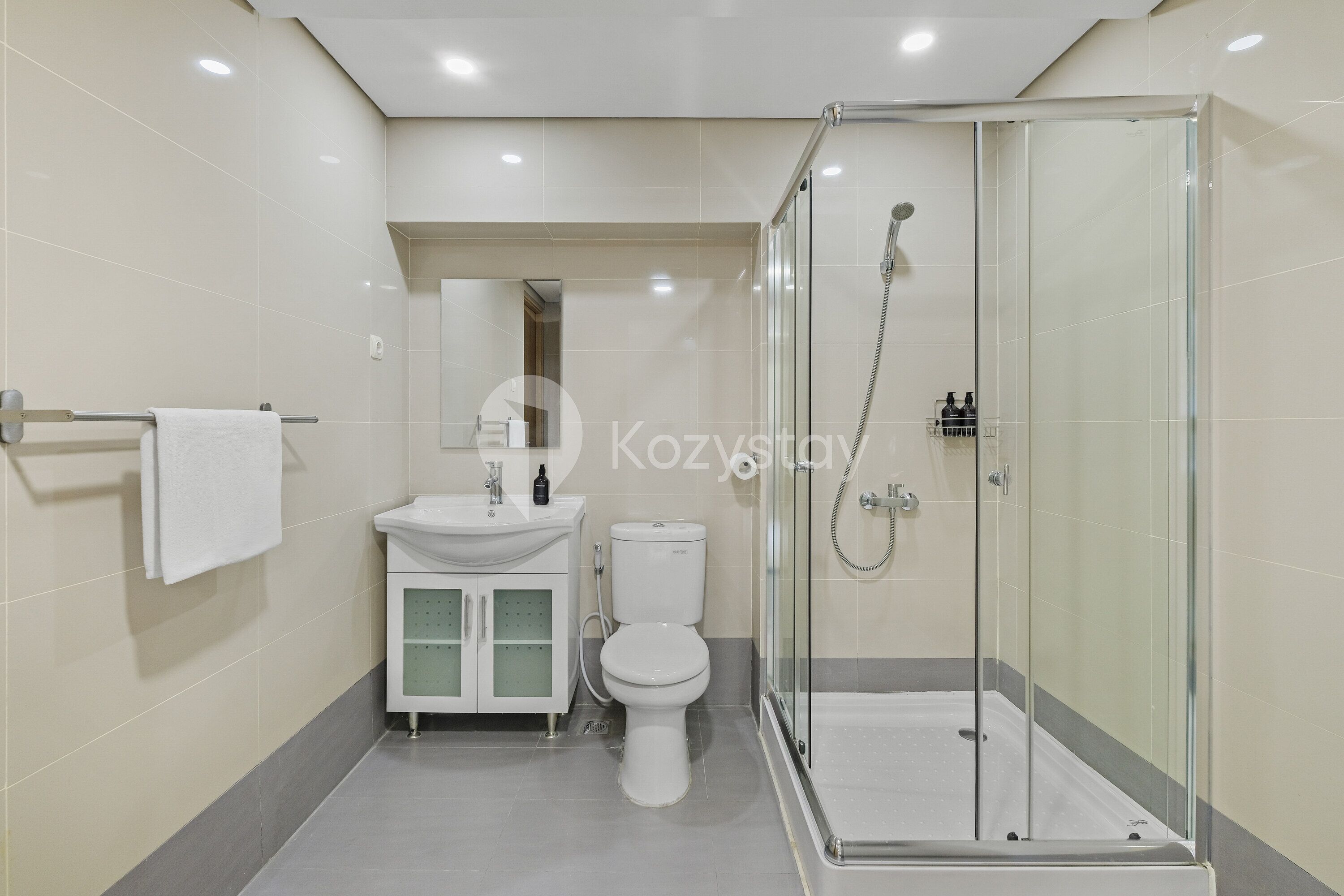 A modern bathroom with a glass-enclosed shower, a white toilet, and a vanity with a sink and cabinet.