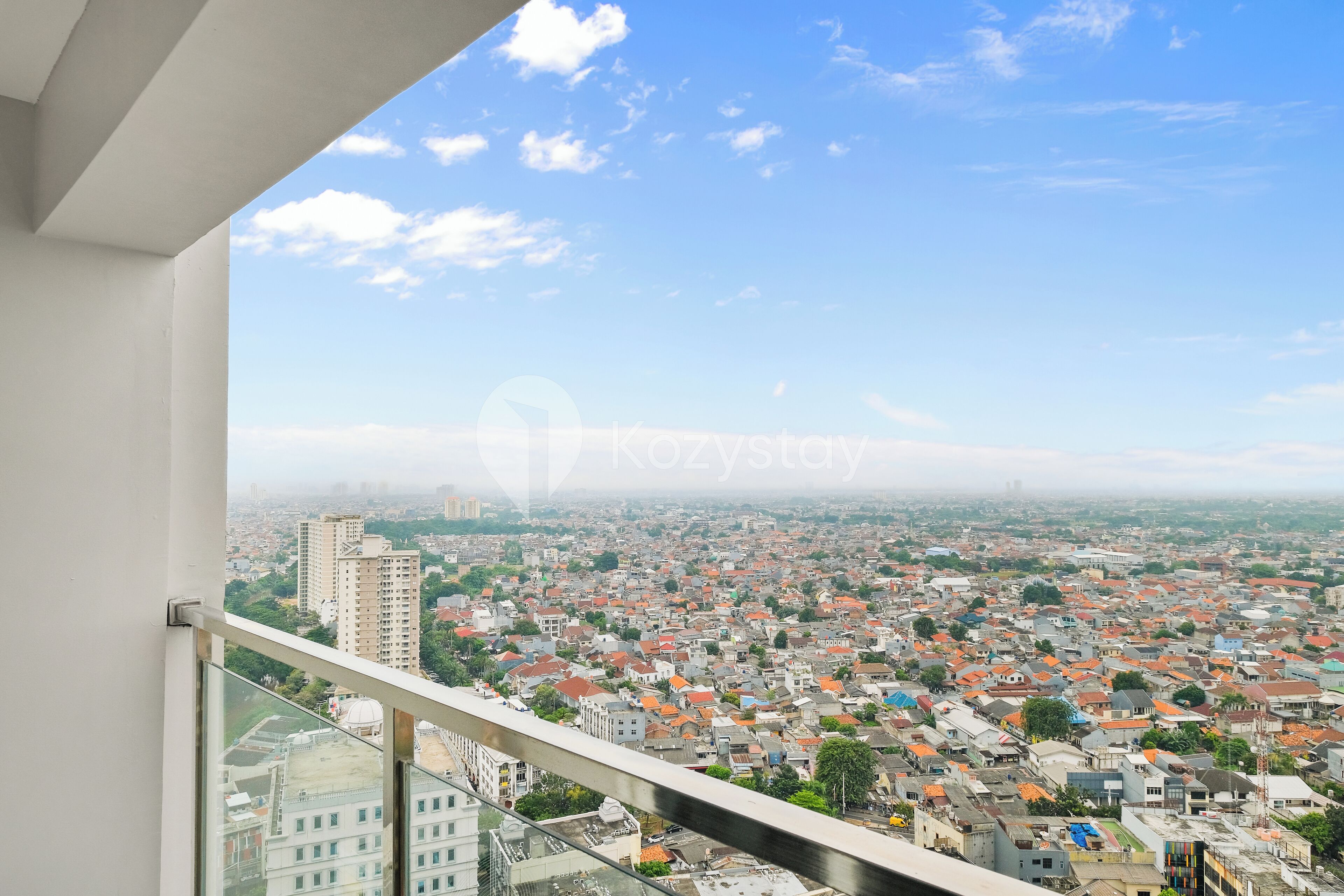 A cityscape viewed from a balcony with a clear sky.