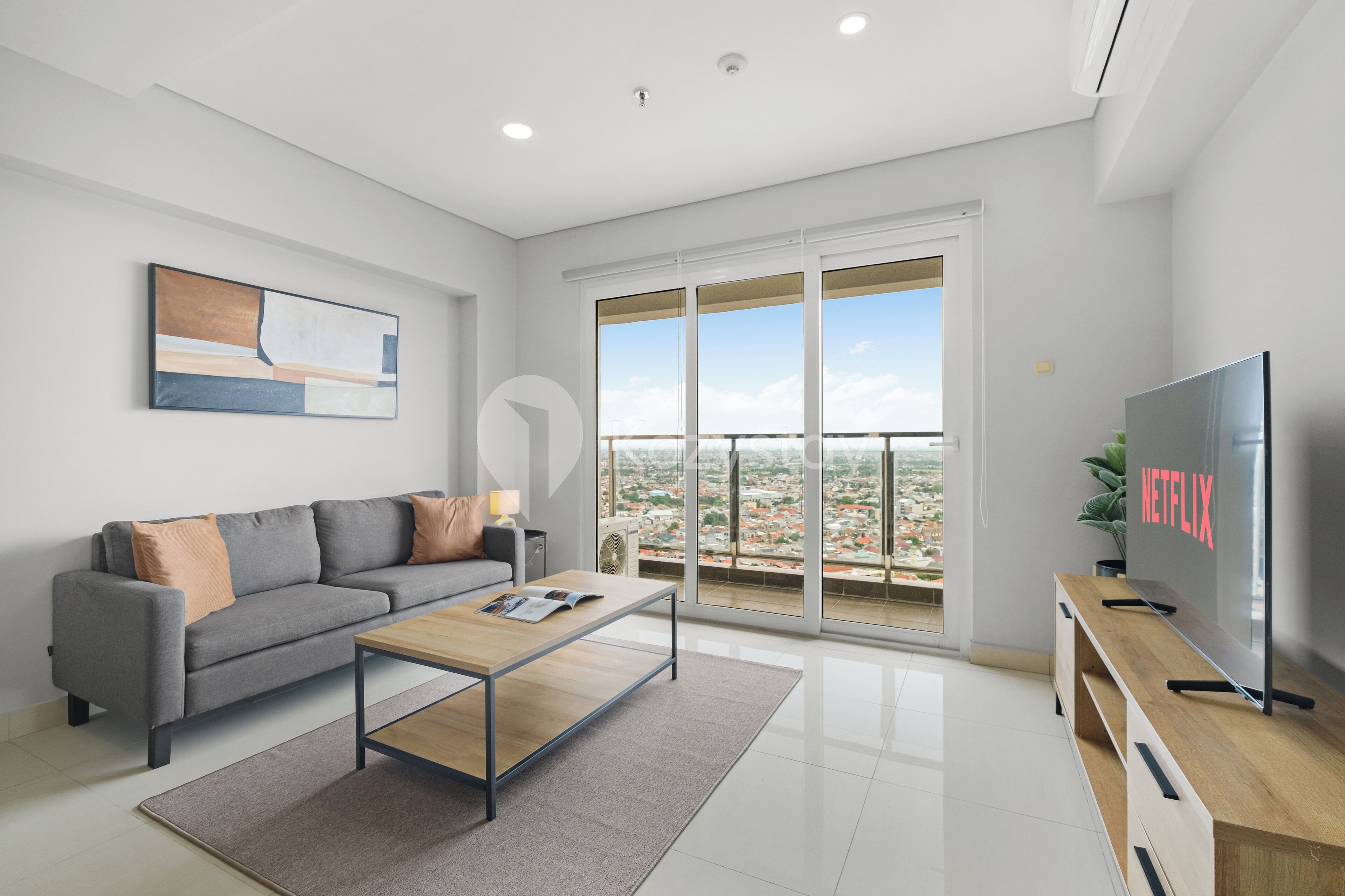 A modern living room with a grey sofa, a wooden coffee table, and a large TV on a wooden stand.
