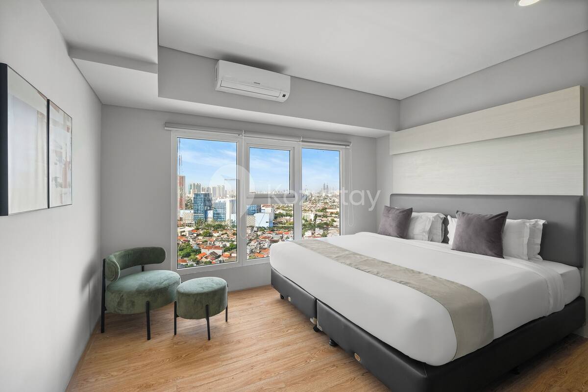 Une chambre moderne avec un grand lit, une vue sur la ville et un fauteuil vert.
