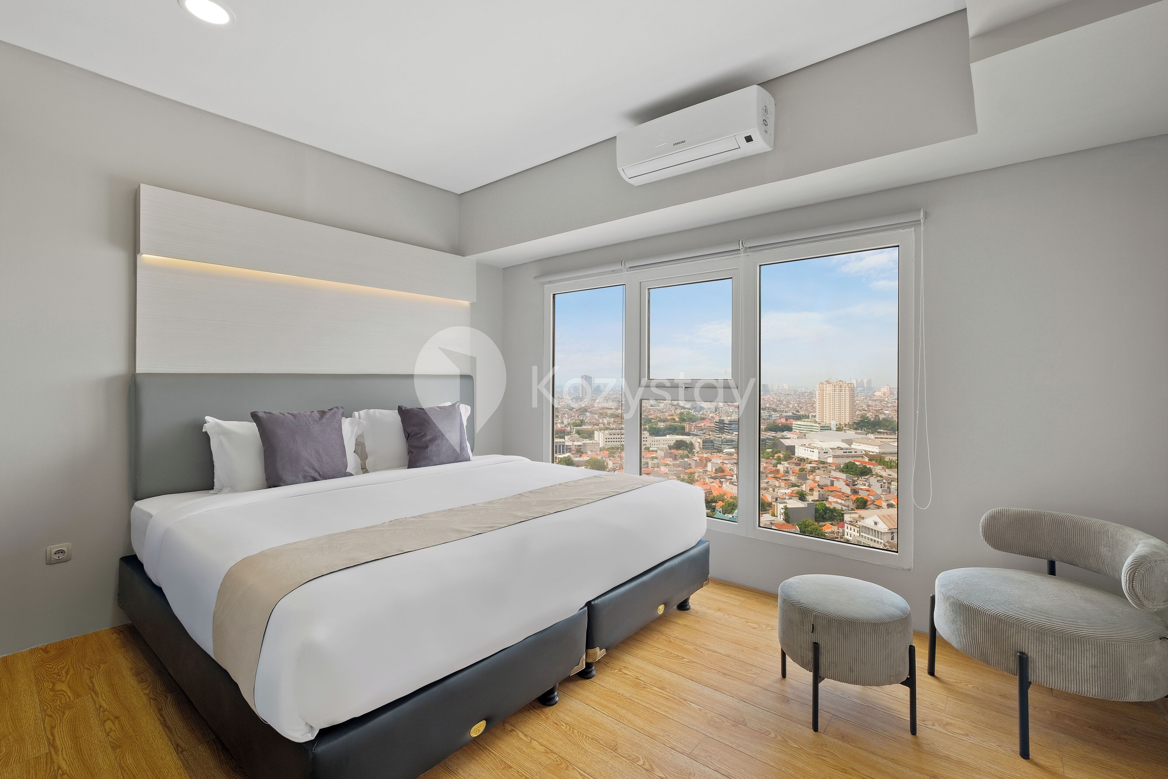 A modern bedroom with a large bed, a view of the city, and a window.