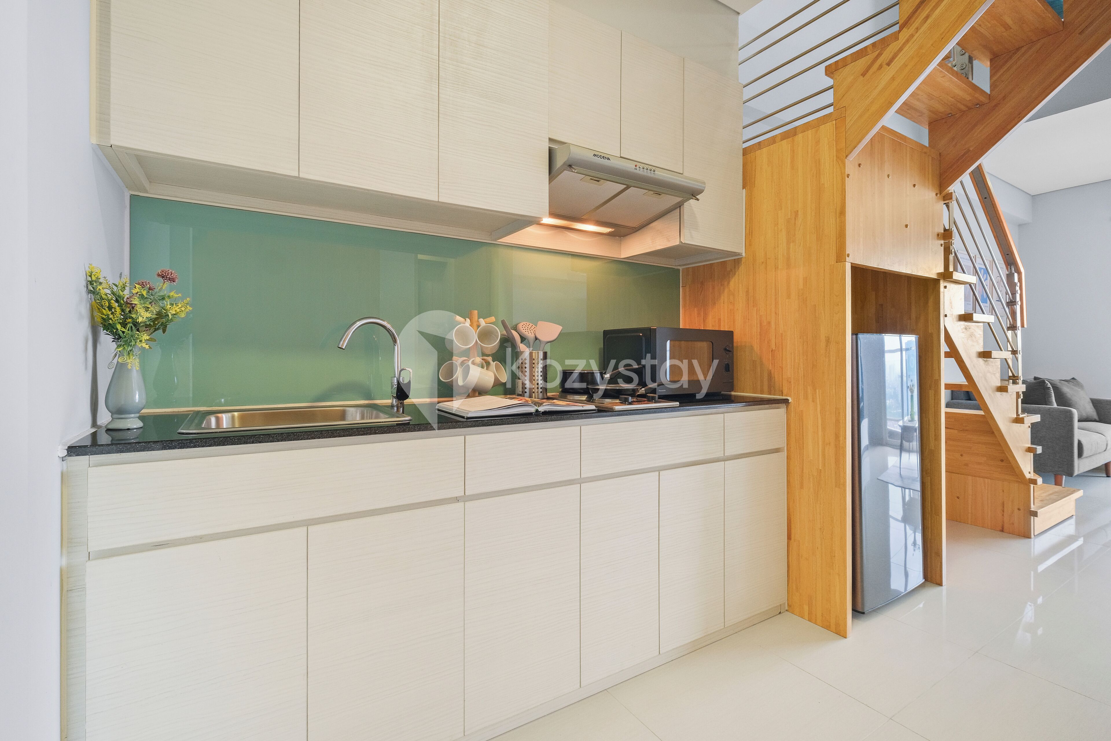Una cocina moderna con armarios blancos, un lavamanos de acero inoxidable y un microondas integrado.