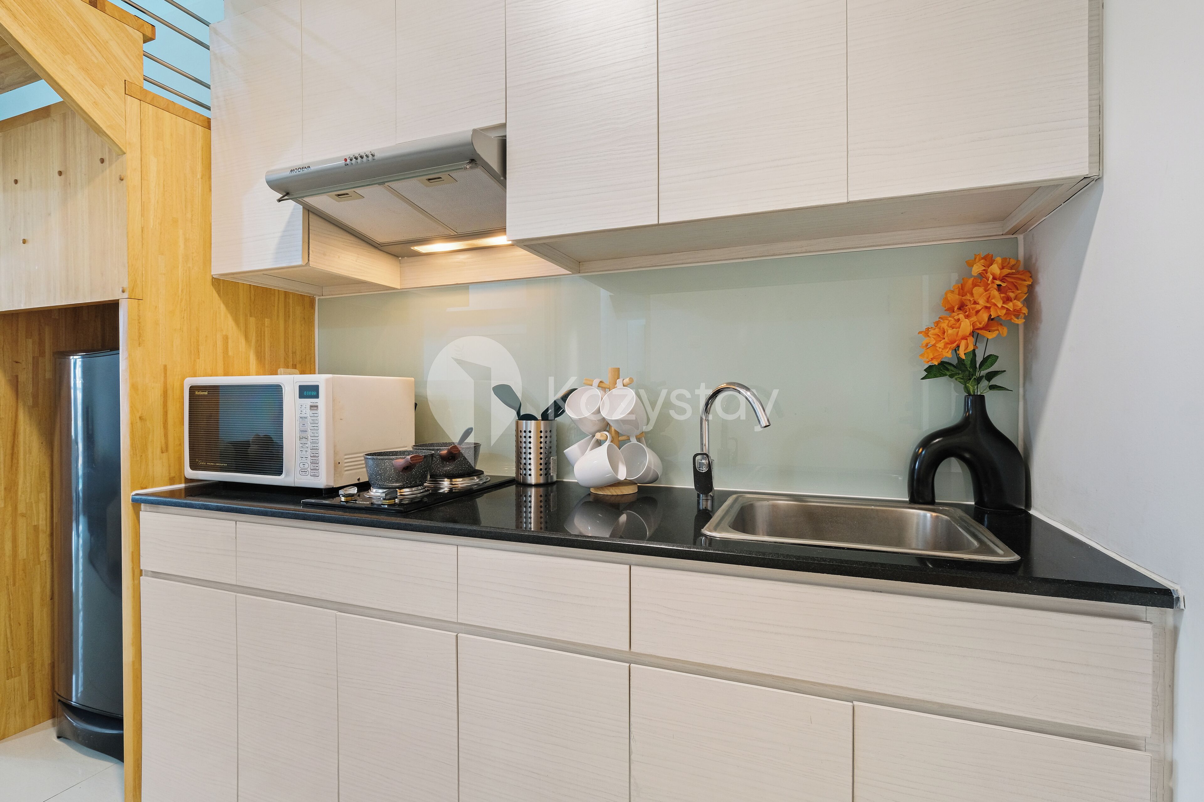 A modern kitchen with a microwave, sink, and wooden cabinets.