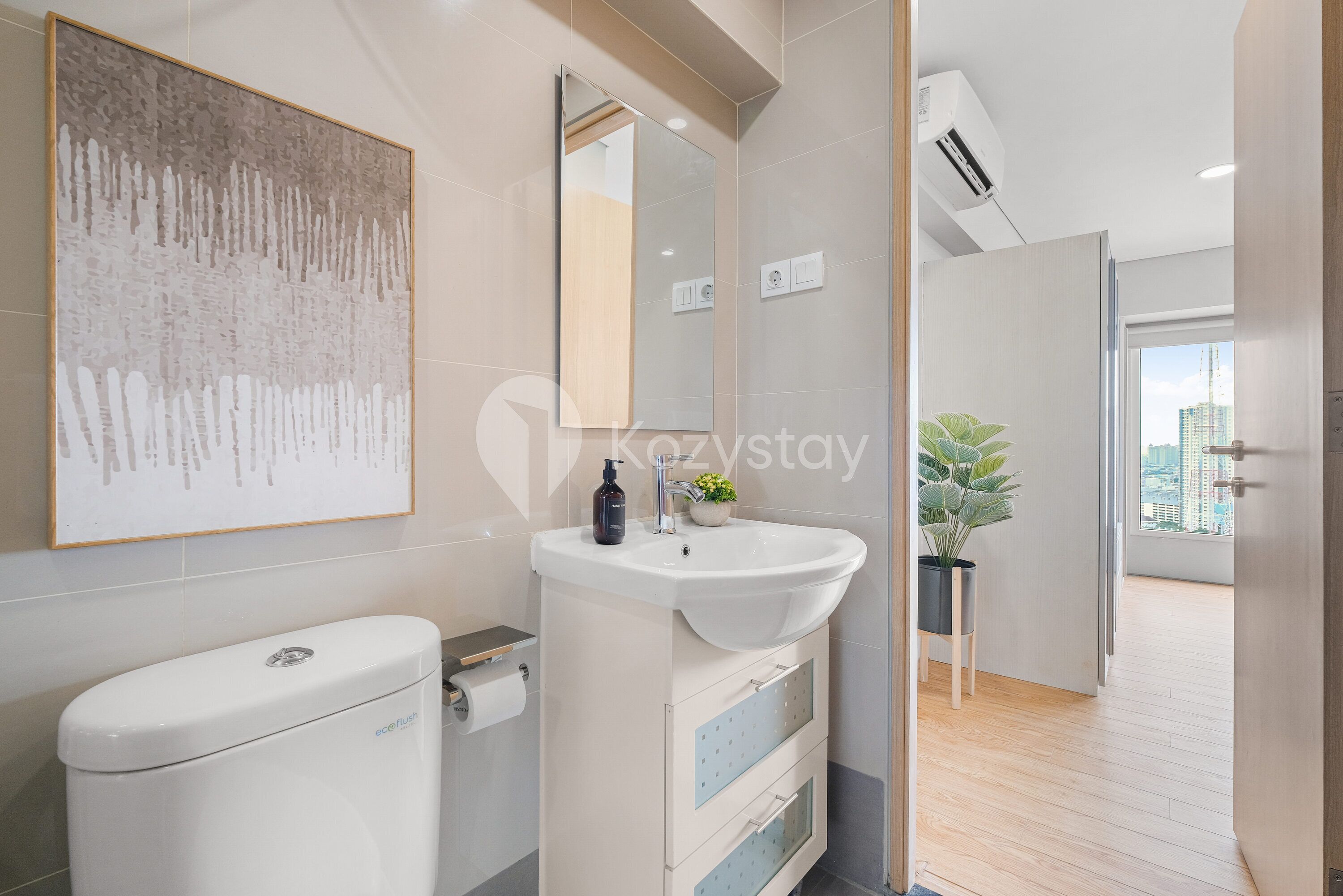 A modern bathroom with a toilet, sink, and mirror. There is a plant and a window in the background.