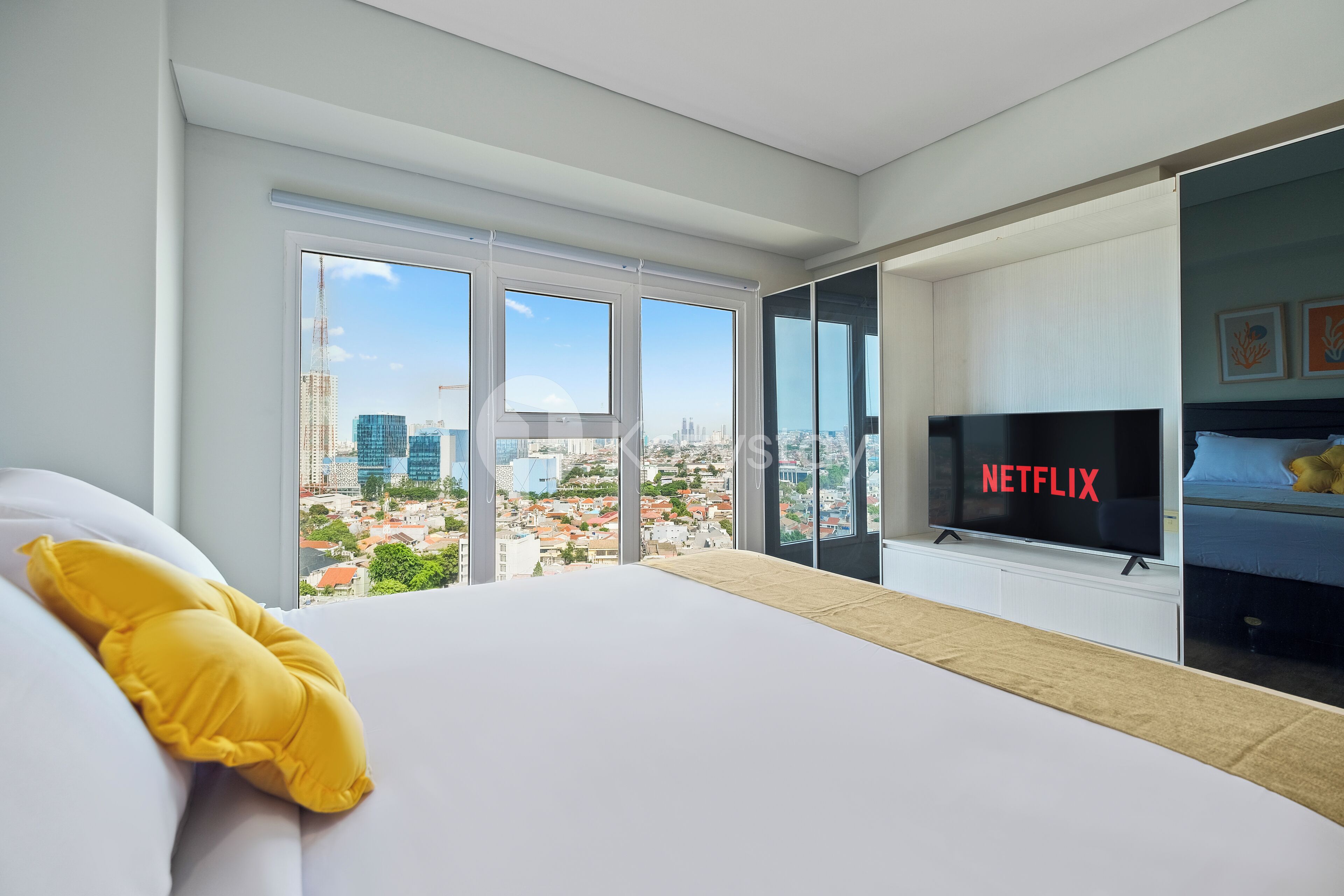 A modern hotel room with a large bed, a TV, and a city view.