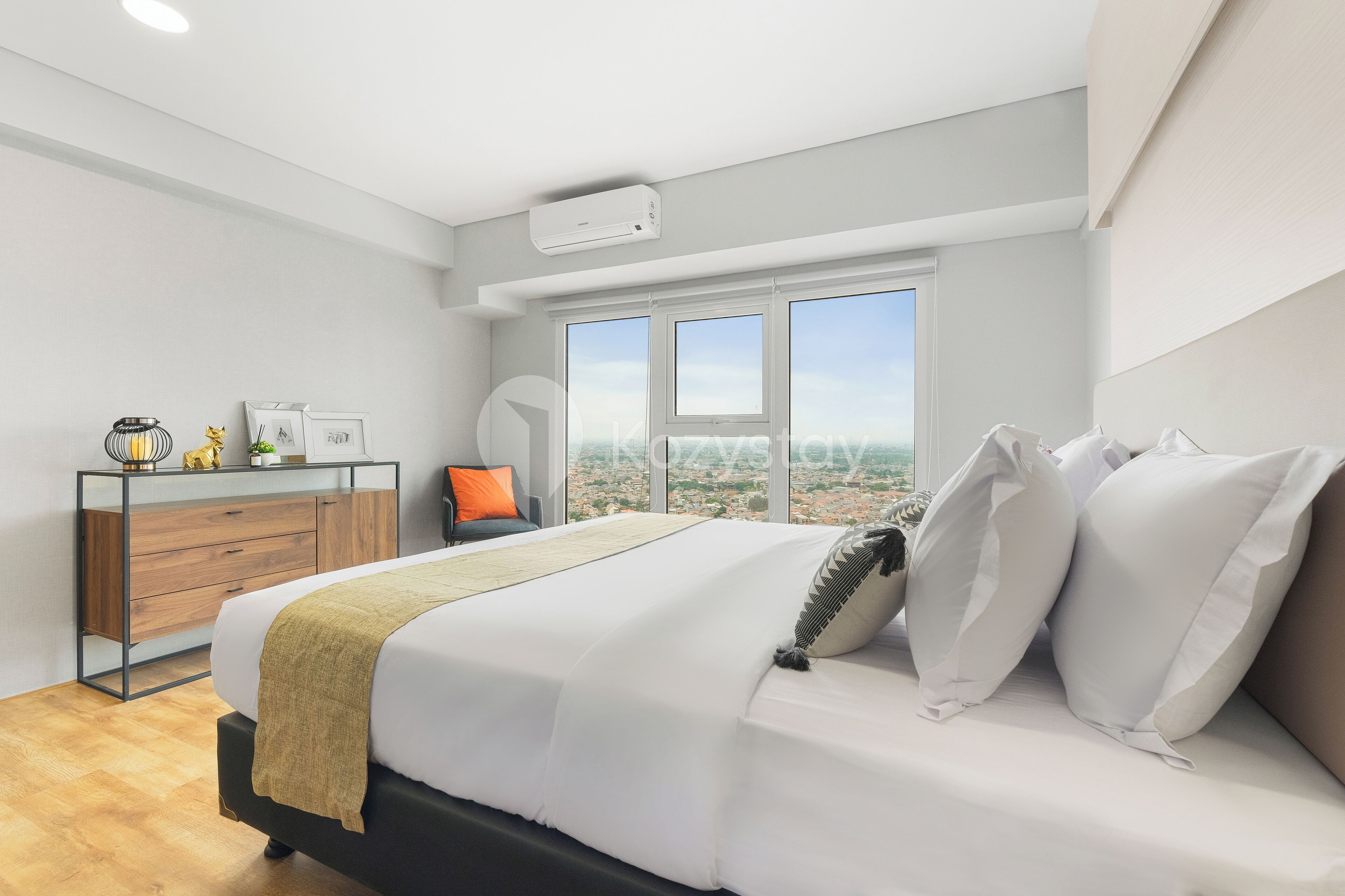 Une chambre moderne avec un grand lit, un bureau avec une chaise et une vue sur la ville grâce à de grandes fenêtres.