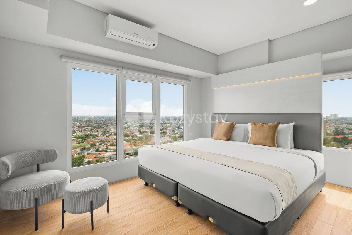 Une chambre moderne dotée d’un grand lit, d’un coin salon et offrant une vue sur la ville.
