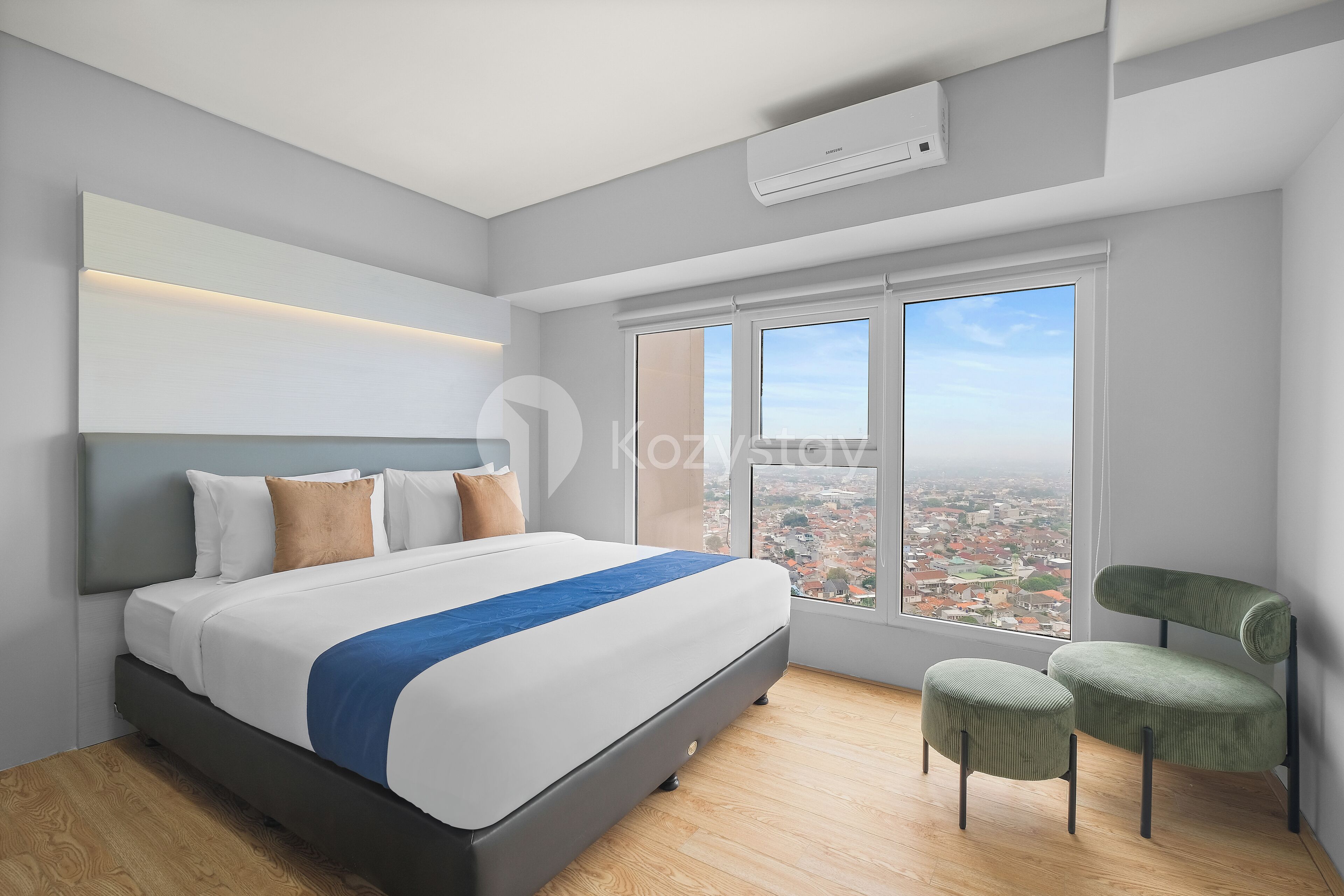 A modern bedroom with a large bed, a view of the city, and a window air conditioner.