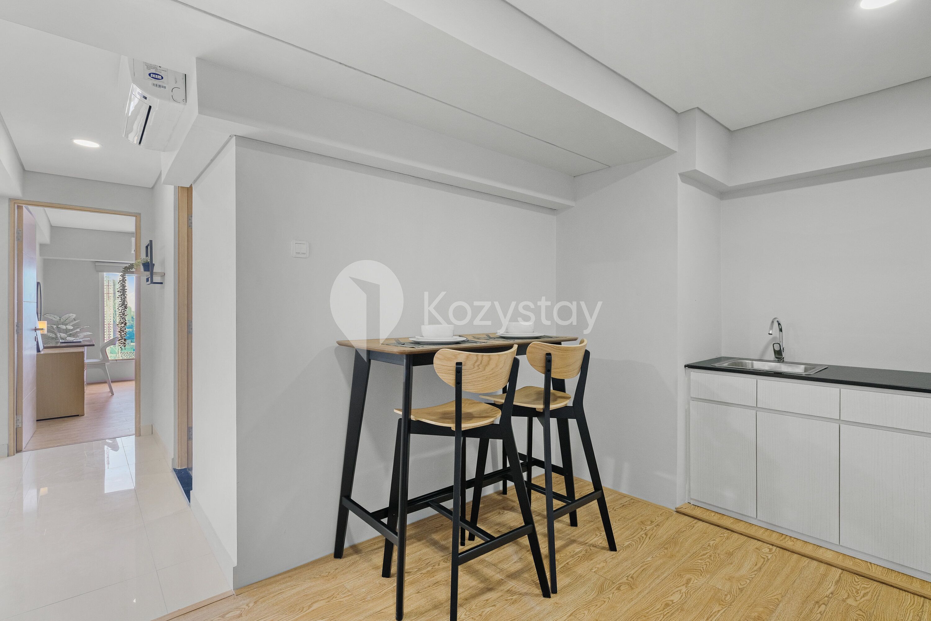 A modern kitchen with white cabinets, a black countertop, and two wooden chairs.