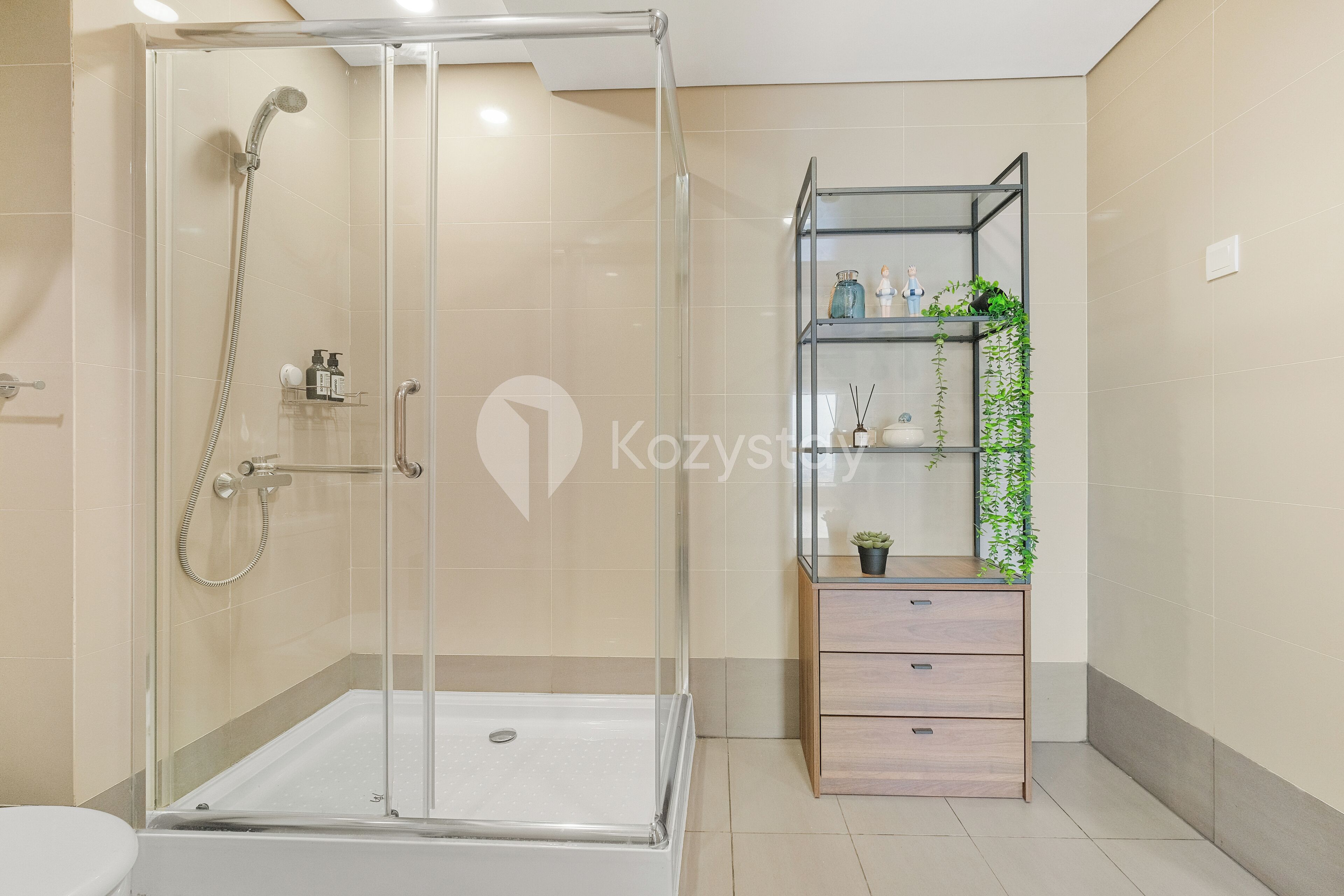 Ein modernes Badezimmer mit einer gläsernen Duschkabine, einem Holzkosmetikschrank mit Schubladen und einem Regal mit Pflanzen.