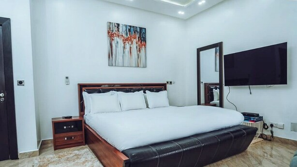 Une chambre à coucher moderne avec un grand lit, un téléviseur à écran plat et un tableau au mur.