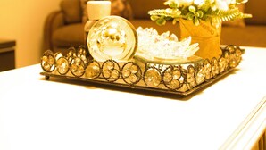 Un plateau orné de divers objets décoratifs est posé sur une table, un vase rempli de fleurs se trouve à proximité, et un chandelier complète l’ensemble dans un salon.