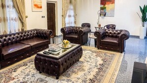 Un salon spacieux avec des canapés en cuir, une table basse et un lustre.