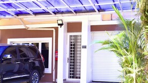 A covered parking area with a blue roof, a black SUV parked, and a potted plant. - Coast to Coast Homes (Abuja)