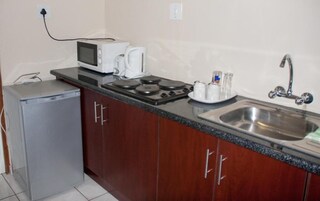 Una cocina compacta con microondas, tostadora, hervidor y pileta.