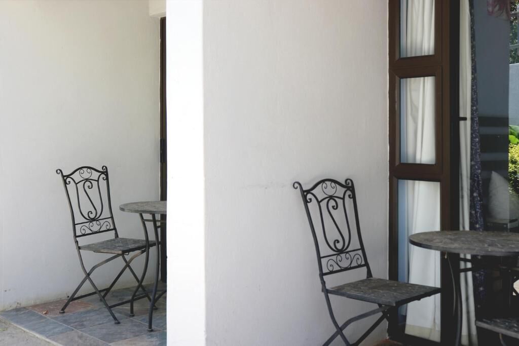 A balcony with two metal chairs and a small round table.