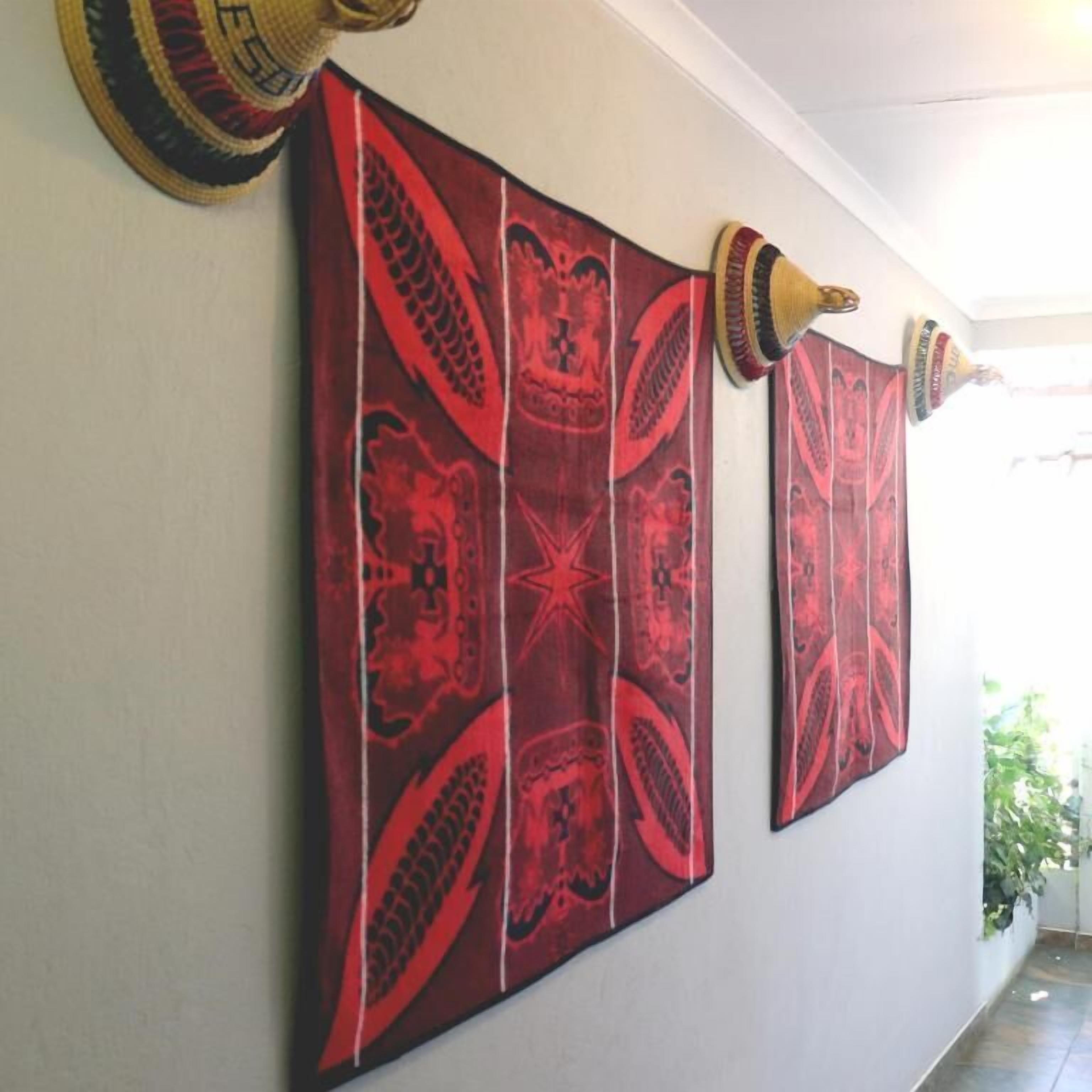 A hallway with two red patterned wall hangings and a pair of decorative wall sconces.