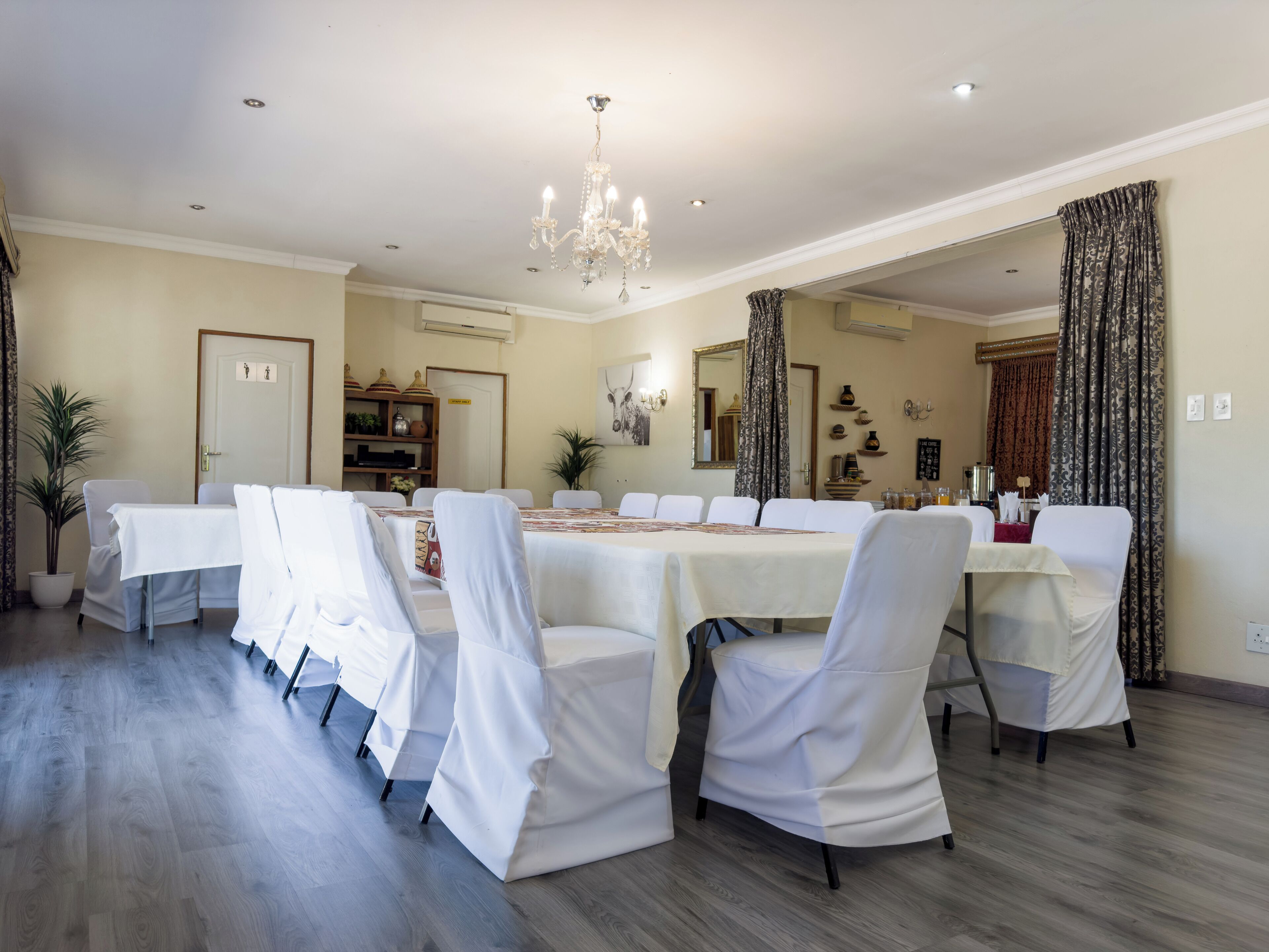 A dining area with a large table, white chairs, and a chandelier.