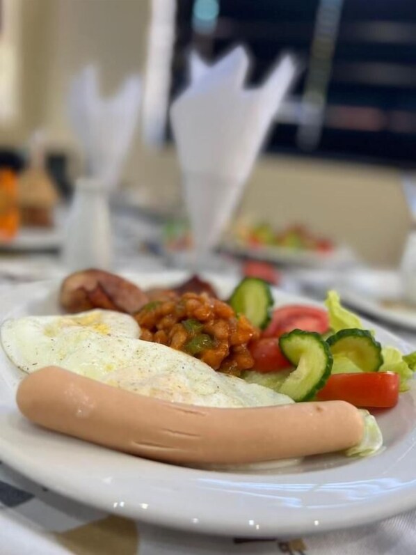 A plate with a sausage, eggs, and vegetables. - Tribute Guest House Matala (Maseru)