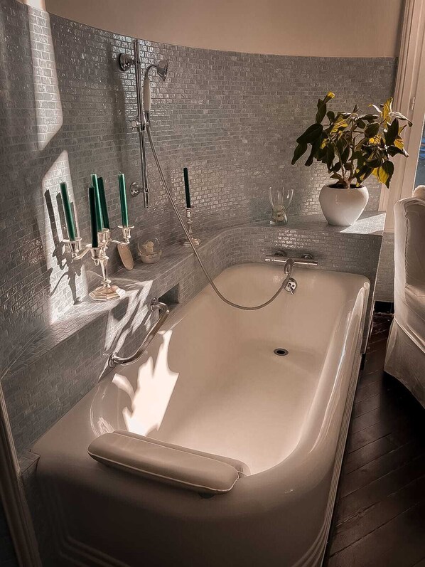 A modern bathroom with a large bathtub, a shower, and a potted plant.