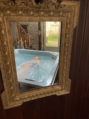 A framed view of a hot tub with a stone wall and wooden staircase in the background.