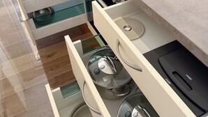 Una cocina moderna con estufa integrada, varios cajones y un armario con puerta de vidrio.