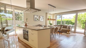 A modern kitchen with a central island, a dining area with chairs, and a sofa.