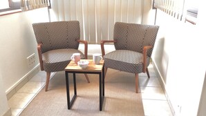Two patterned armchairs facing each other with a small table between them, a bowl, and two mugs on the table.