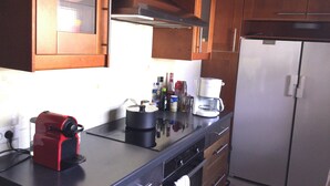 A kitchen with wooden cabinets, a coffee maker, a red appliance, and a refrigerator.