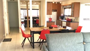 A dining area with a wooden table, red chairs, and a grey sofa.