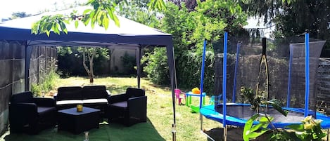 A covered patio area with outdoor furniture and a trampoline.