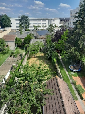 A residential area with a garden, a trampoline, and a building with multiple windows in the background. - Appart cosy-4 pers-centre ville-jardin-wifi (Châteauroux)