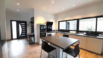 Une cuisine moderne dotée d’un grand îlot central, d’un four encastré et d’une fenêtre offrant une belle vue.