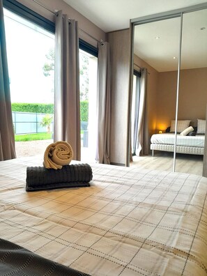 Een hotelkamer met een groot bed, uitzicht op de omgeving en een schuifdeur naar een balkon.