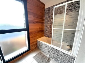 Een badkamer met een houten wand, een glazen douchecabine en een betegelde vloer.