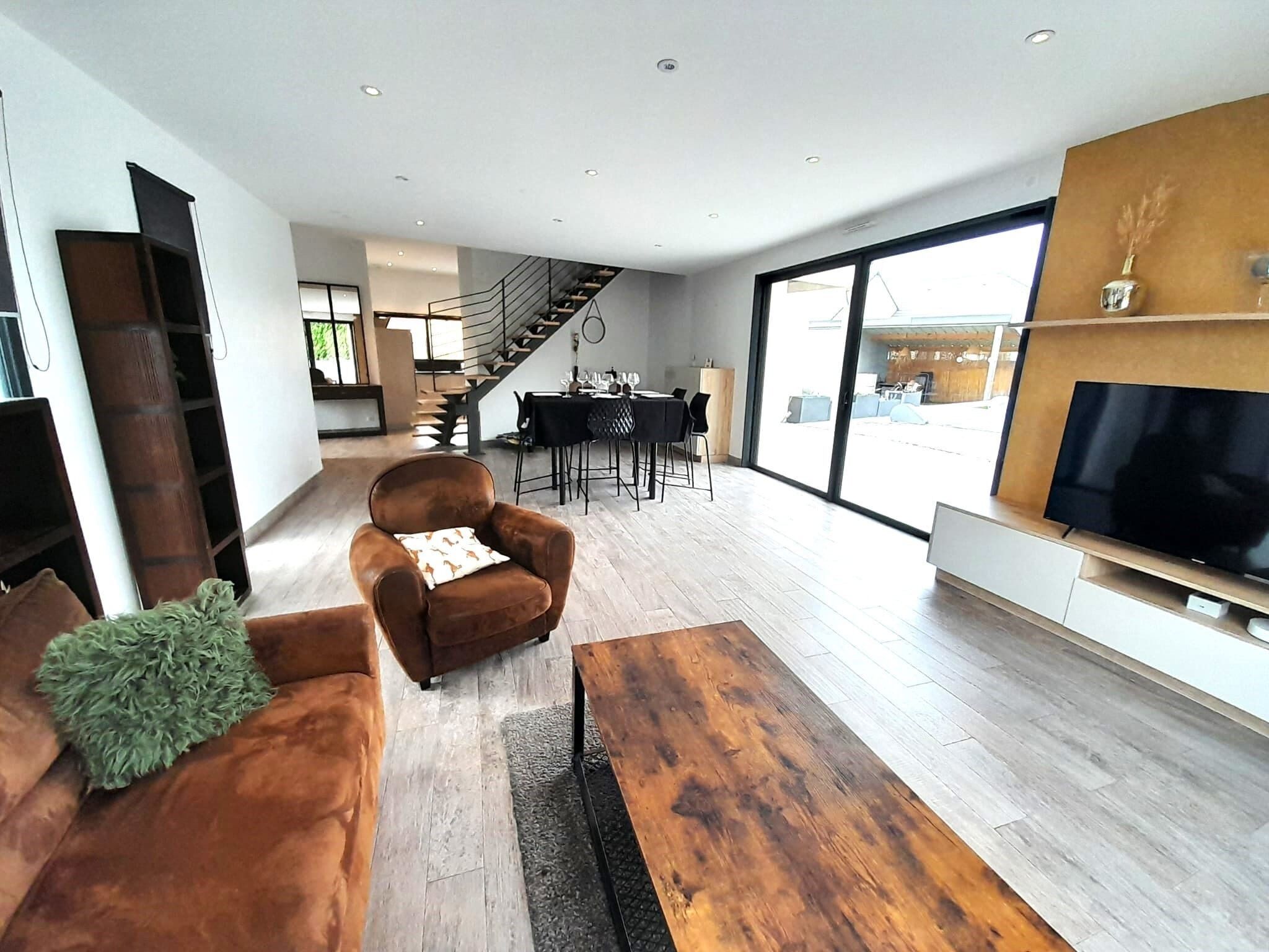 Un salon moderne avec un canapé en cuir marron, une table basse en bois et un téléviseur à écran plat fixé au mur.