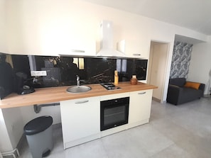 A compact kitchen with a black and white color scheme, a built-in oven, and a small sink. - Élégant appartement- wifi- Vatan centre (Vatan)
