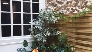 A corner with a window, a stone wall, and a wooden planter with plants.